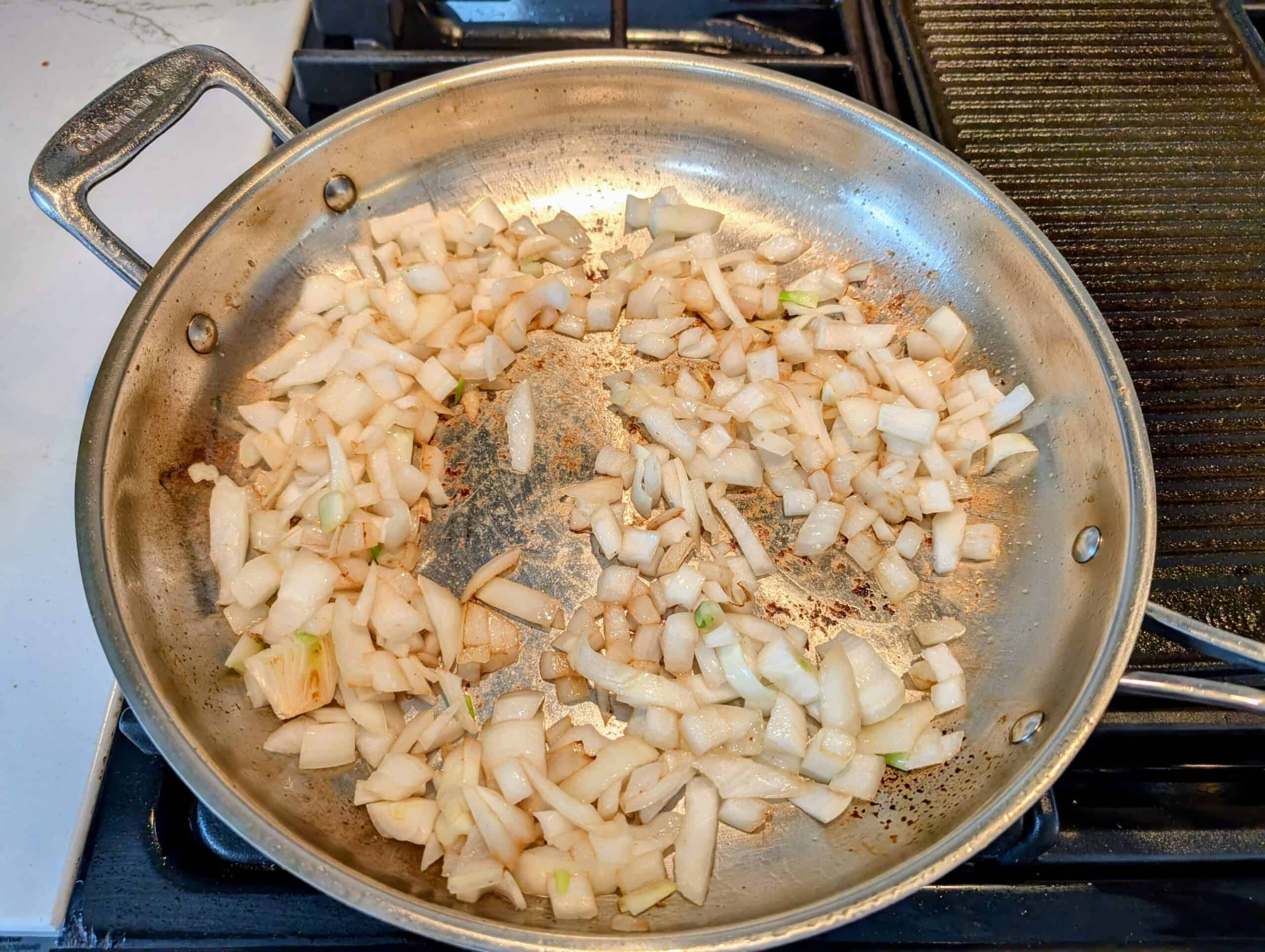 stove top skillet with sautéed onions cooked in rendered pork fat 