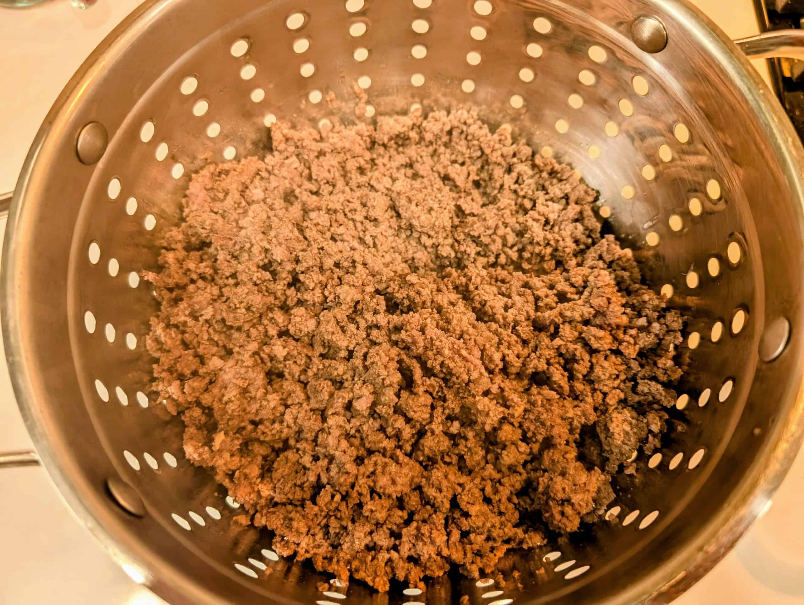 Straining fat from ground beef in a stainless steel strainer