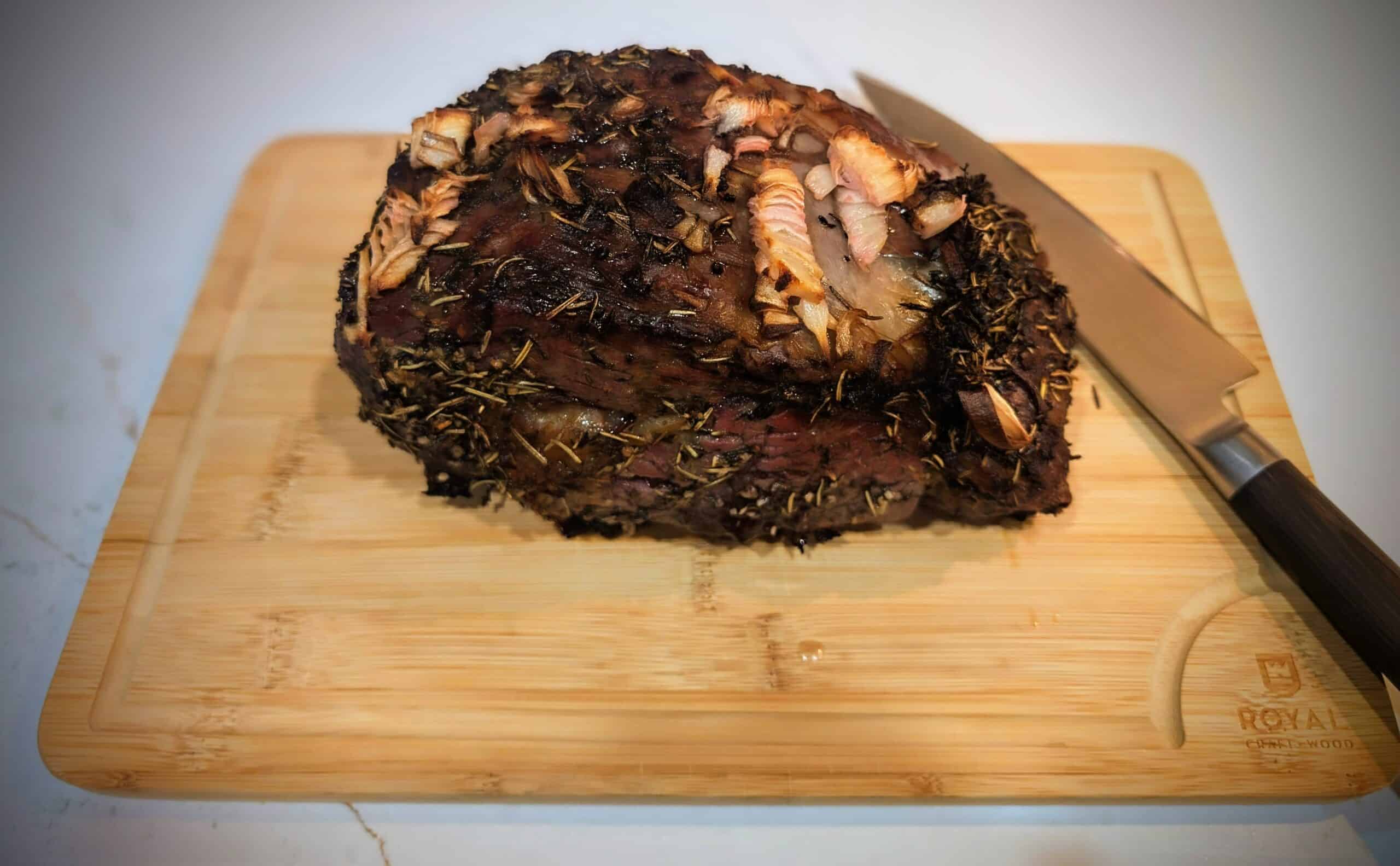 Ribeye Roast resting on a wooden cutting board after baking in the oven.