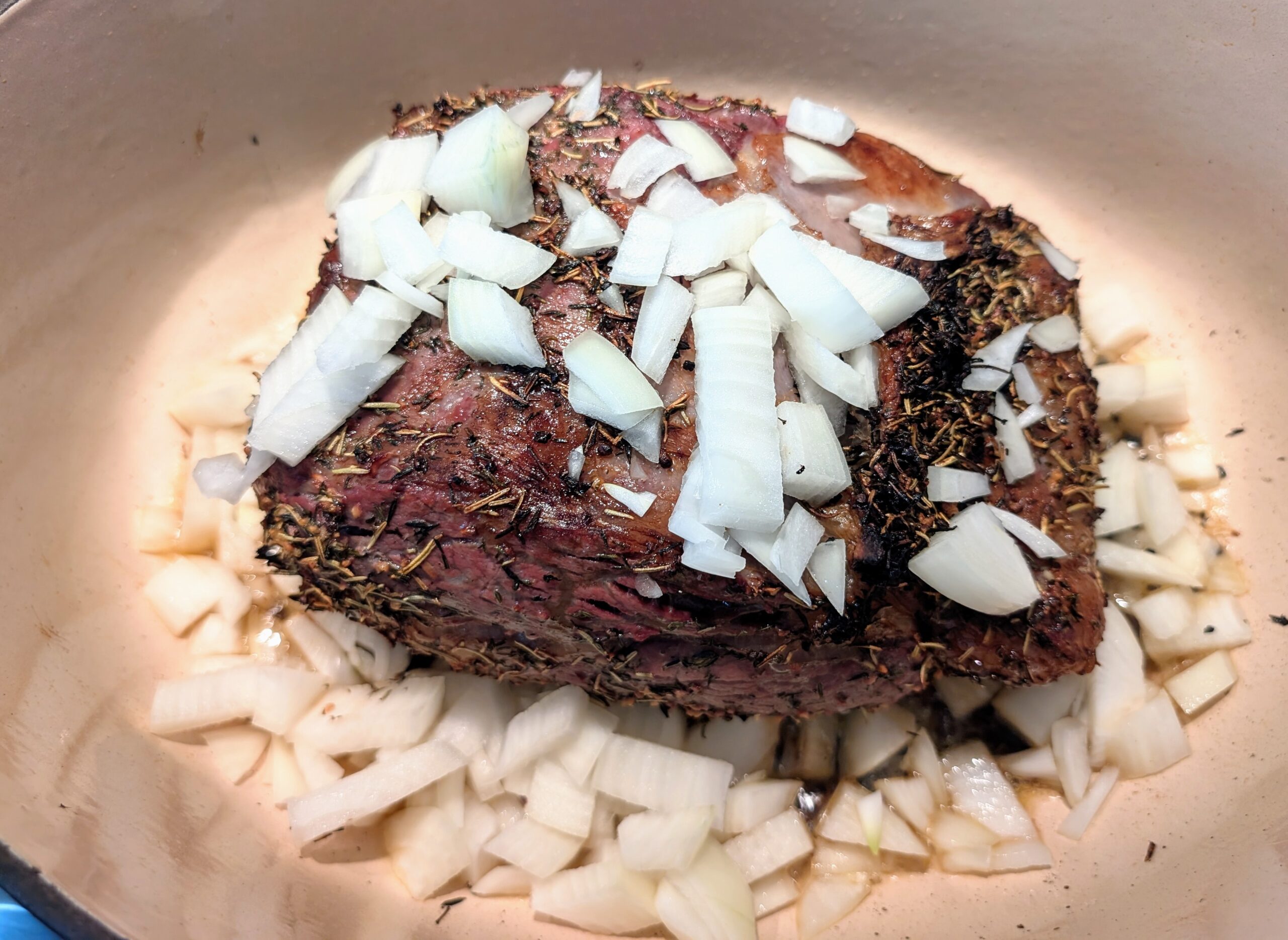 Ribeye roast cooking, added yellow onions to the roasting pan 