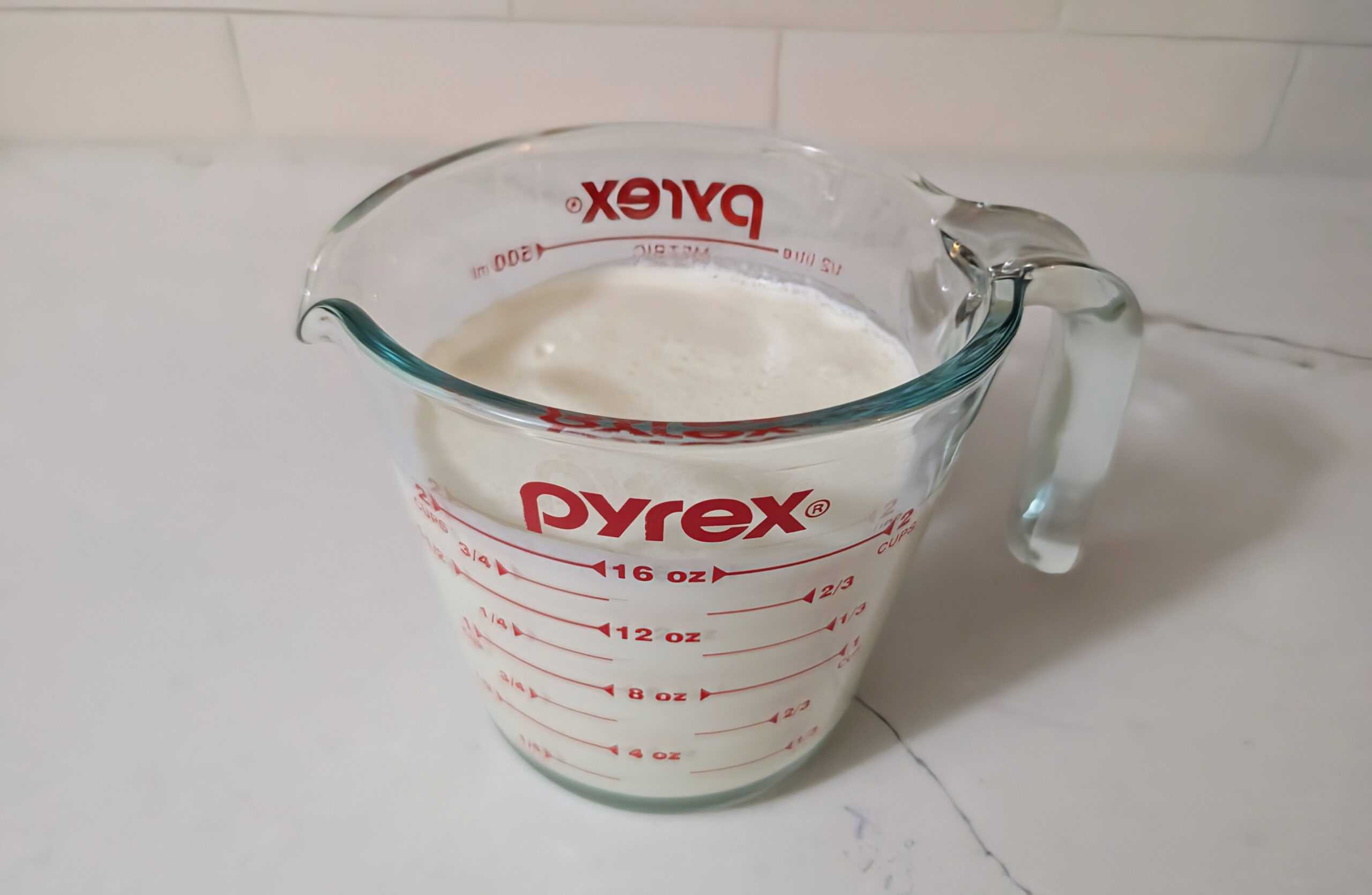 Dairy for sour cream being measured in a Pyrex measuring cup 