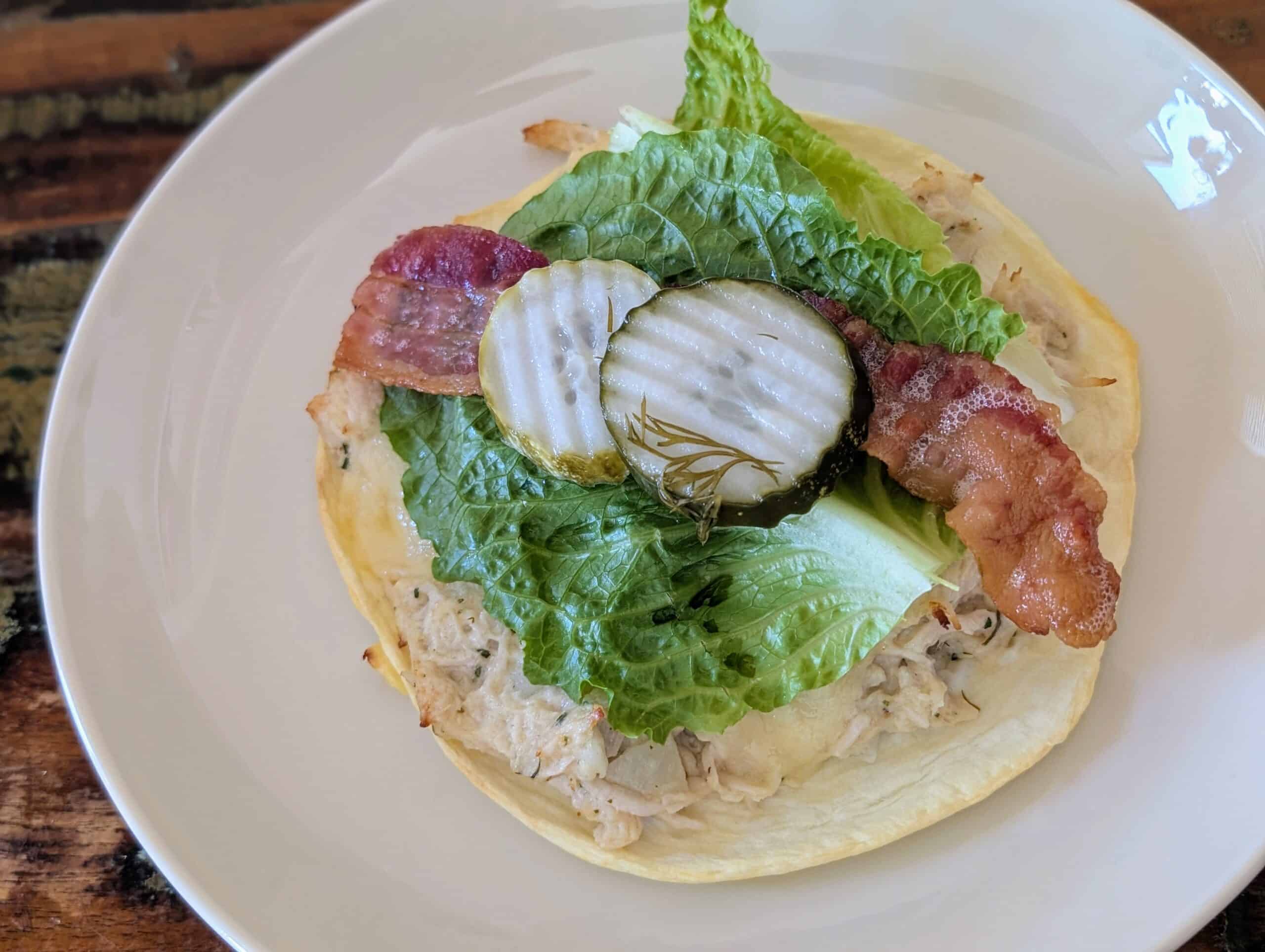 Chicken salad on toasted egg wrap with cheese, romaine lettuce, bacon and pickles